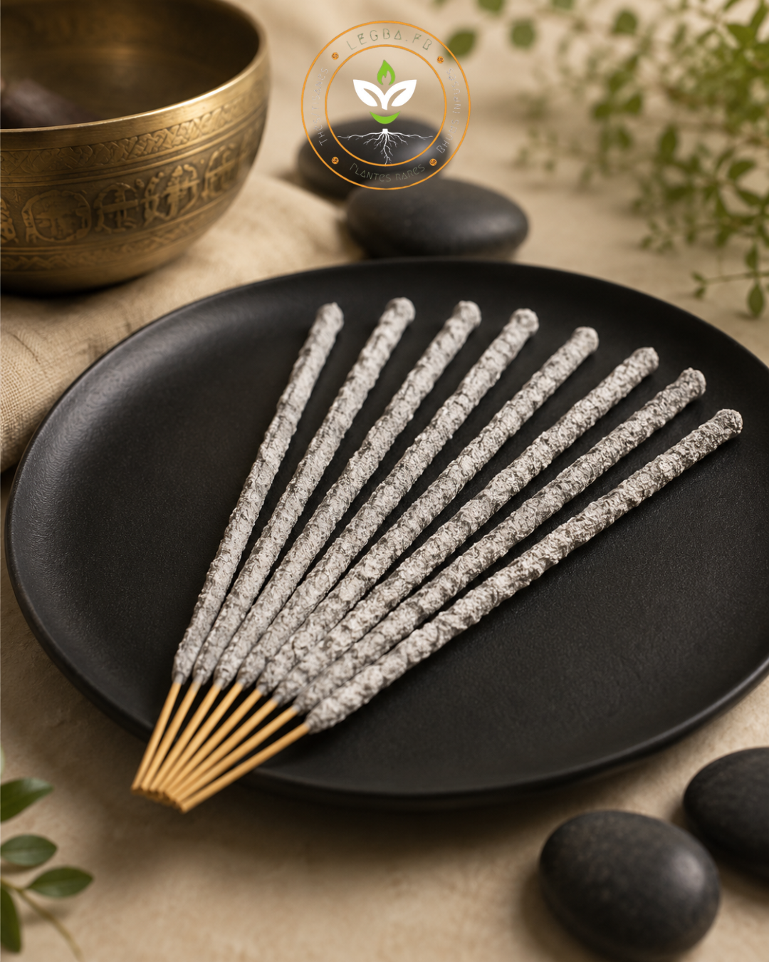 Encens Yagra LEGBA en bâtonnets blancs, présenté sur une assiette noire avec bol doré et galets, pour une ambiance douce et rituelle